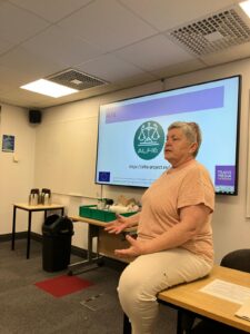 Pilar Orero speaking during the Industry-Academic Collaboration workshop at the EST Congress 2025, with the ALFIE project logo displayed on the screen behind her.