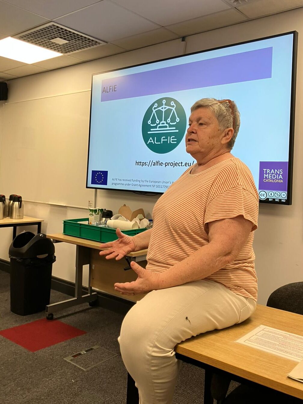 Pilar Orero speaking during the Industry-Academic Collaboration workshop at the EST Congress 2025, with the ALFIE project logo displayed on the screen behind her.