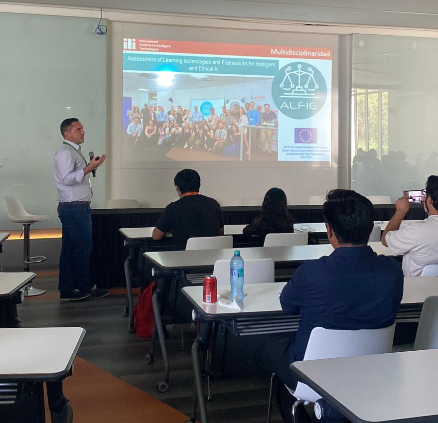 Dr. Juan Antonio Recio García presents in a classroom during ICAIMH 2025. He stands beside a projected slide featuring the ALFIE project and a group photo of the research team. Attendees are seated, listening, and some are taking photos or notes.