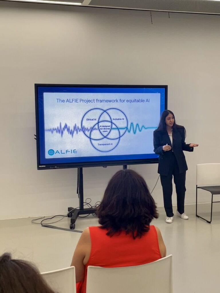 Here is a short alt text in English: > Reyhaneh presenting a slide titled "The ALFIE Project framework for equitable AI," featuring a Venn diagram with pillars for Ethical AI, Inclusive AI, and Transparent AI.