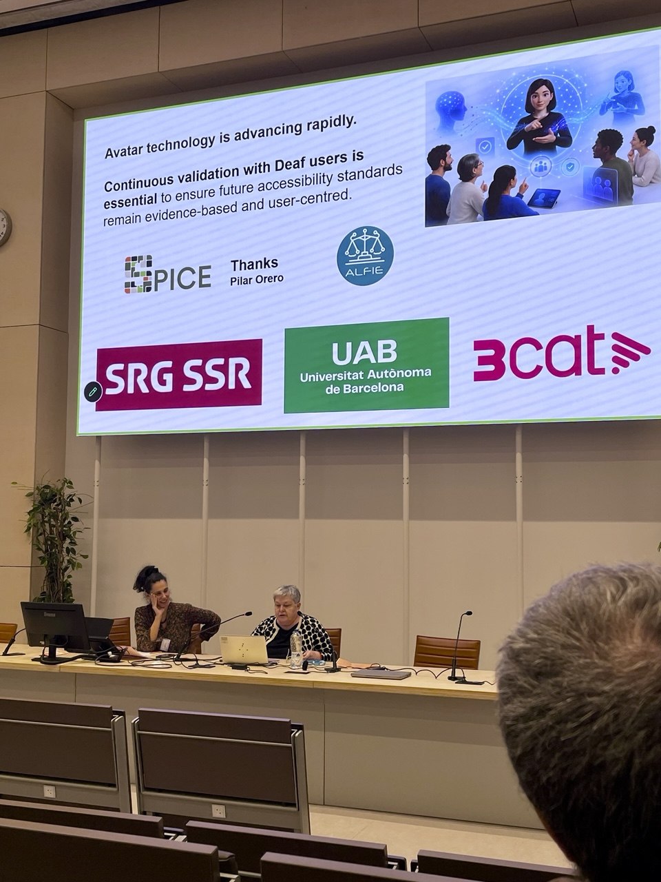 Pilar Orero seated at a conference panel table presenting a slide on sign language avatar technology. The slide text reads: "Avatar technology is advancing rapidly. Continuous validation with Deaf users is essential to ensure future accessibility standards remain evidence-based and user-centred." Logos for SPICE, ALFIE, SRG SSR, UAB, and 3Cat are visible on screen